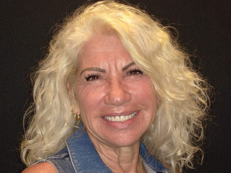 The image shows a woman with blonde hair smiling at the camera.