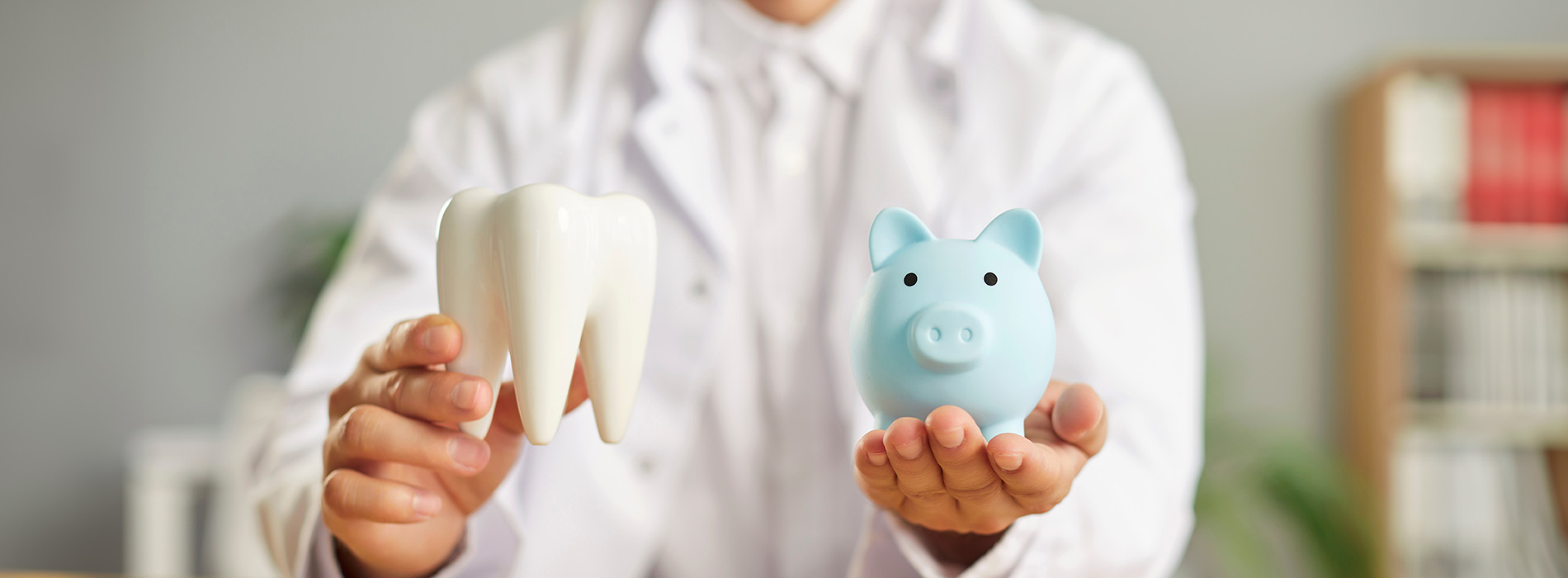 A dentist holding up two toothbrushes with cartoon pig heads on them.