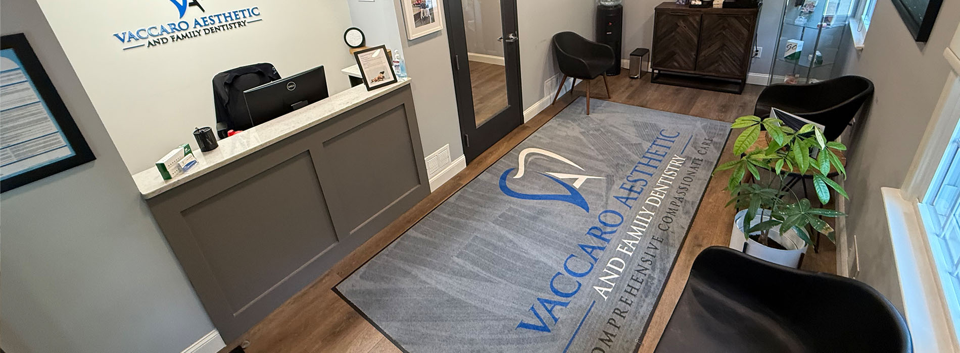 The image shows an interior view of a professional office space with a reception area featuring a desk and chair, a carpeted floor, and a sign with text that reads WAGER ASSOCIATES.