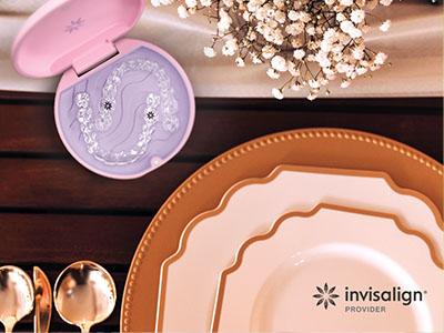 This image features a close-up view of a table setting with a focus on a pink makeup compact, a set of plates, and a spoon rest, all arranged on a wooden surface.