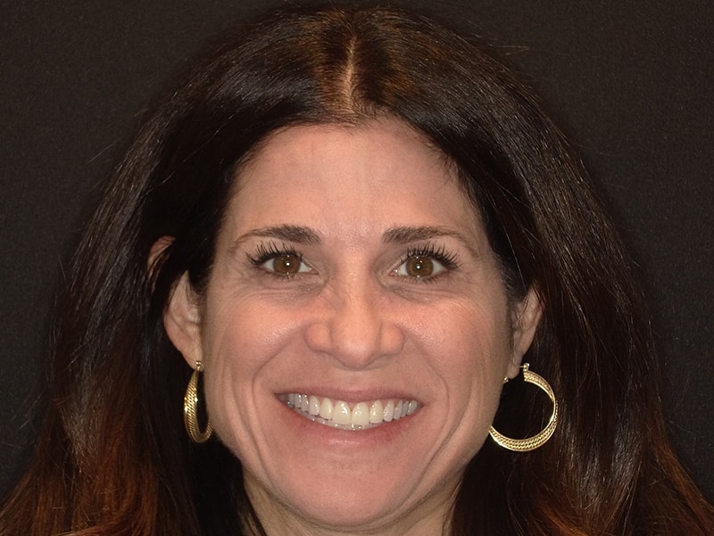 The image shows a woman with long hair smiling at the camera.