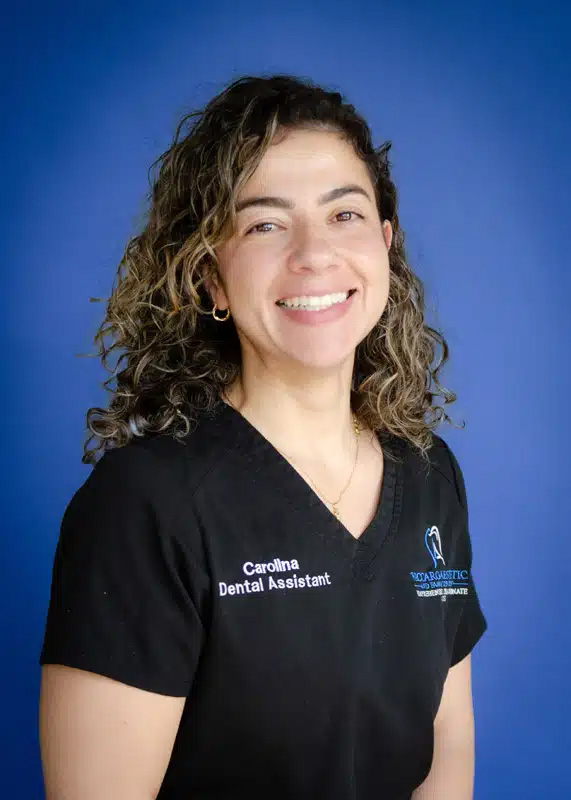 The image features a smiling woman wearing a white lab coat with a name tag, standing against a blue background.
