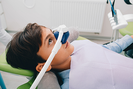 A young person sitting in a dental chair with a dental device on their face.